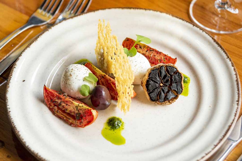 Caprese mussarela de búfala tomate confitado, alho negro, molho pesto e telha de parmesão. Foto: Fernando Pires