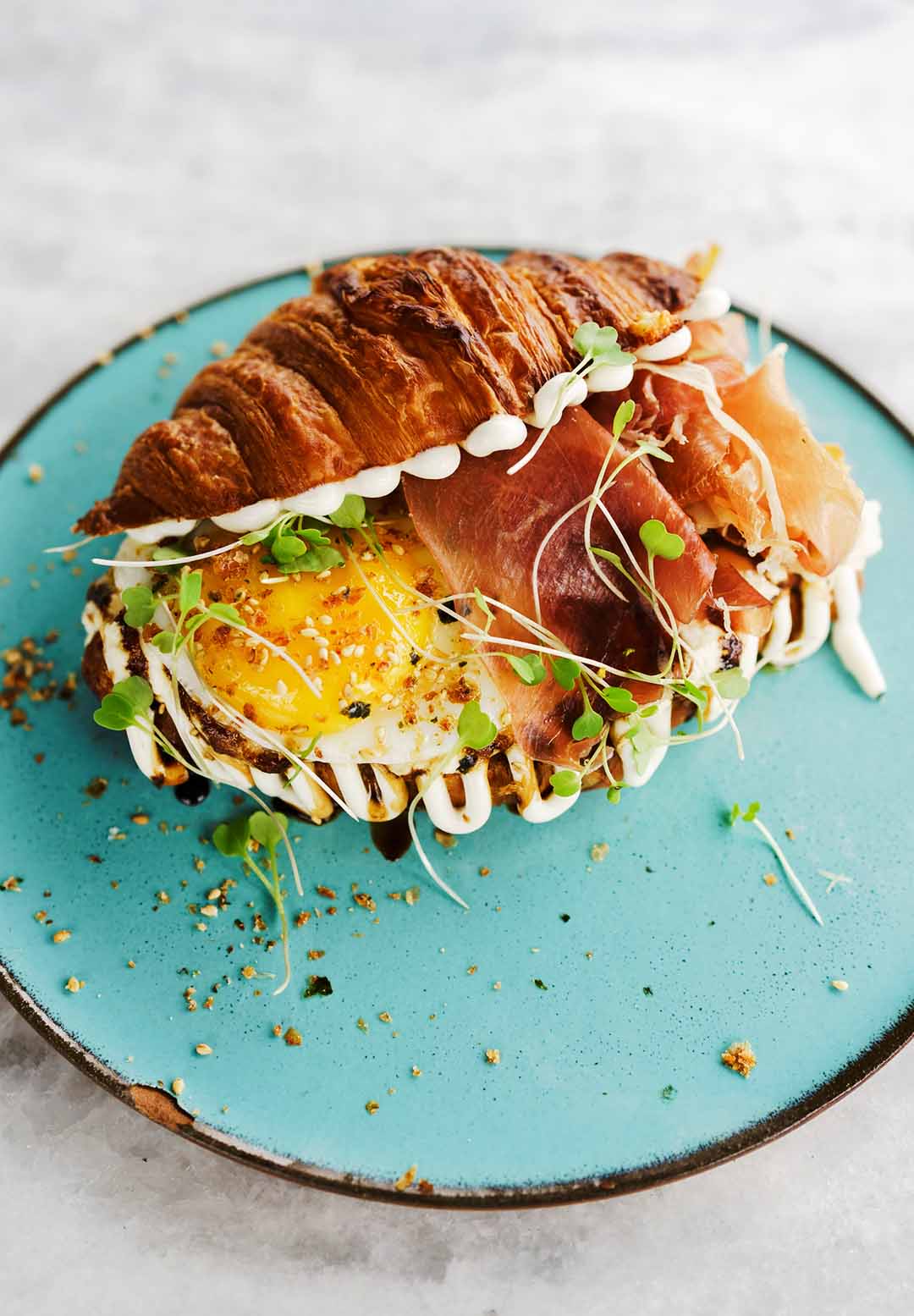 Croissant com presunto cru, ricota da casa, redução de aceto balsâmico, ovo de gema mole, pesto de rúcula e aioli, do Mezanino. Foto: Guilherme Kapanema