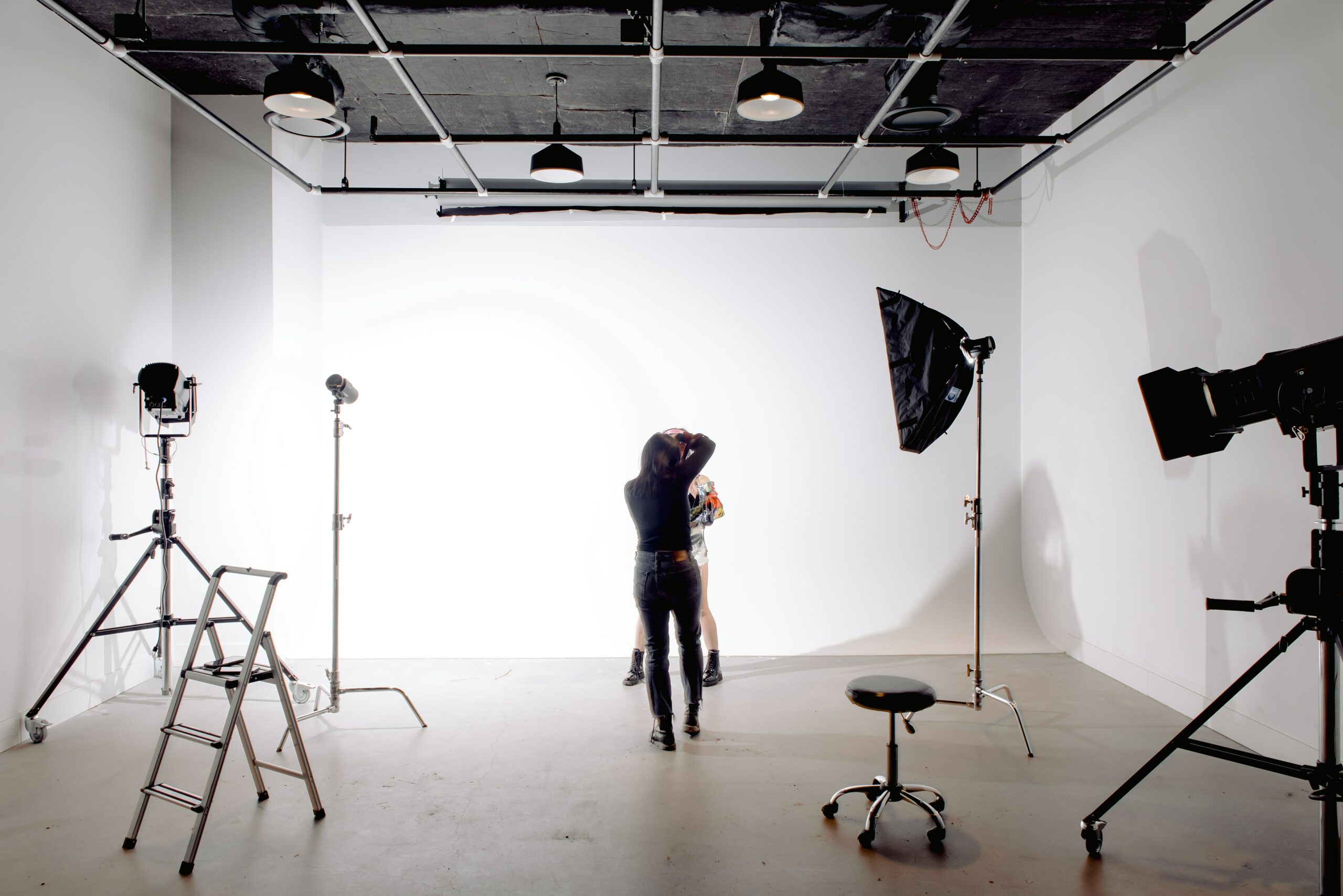 Fotógrafo profissional tirando foto de uma modelo durante sessão de fotos em estúdio, sala branca com luz e equipamento fotográfico