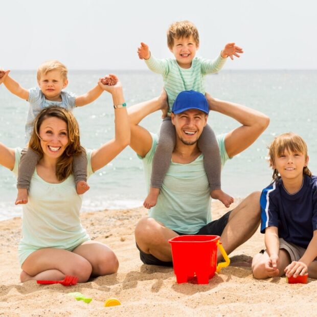 Féria em família. Pais e filhos felizes na praia. Banco de Imagens