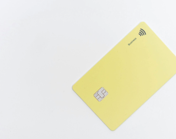 cartão bancário retangular amarelo em uma superfície branca.