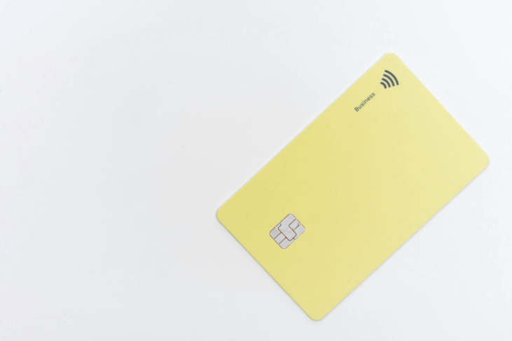 cartão bancário retangular amarelo em uma superfície branca.