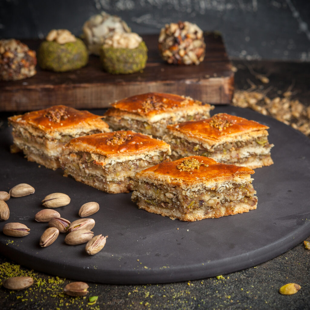 some baklava with cookies on background on a black rounded platform side view.