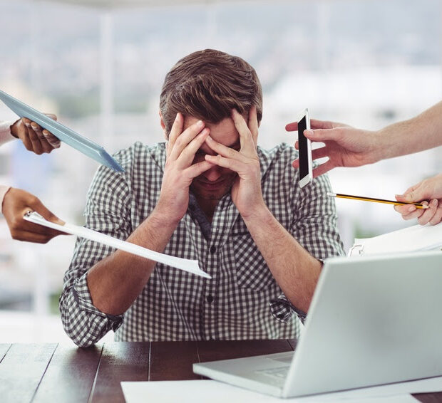 stressed man frustrated with electronic devices in office