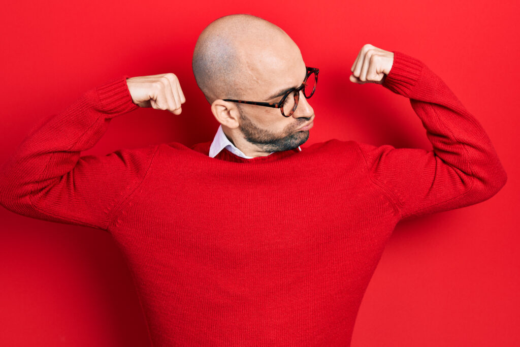 young bald man wearing casual clothes and glasses showing arms muscles smiling proud. fitness concept.