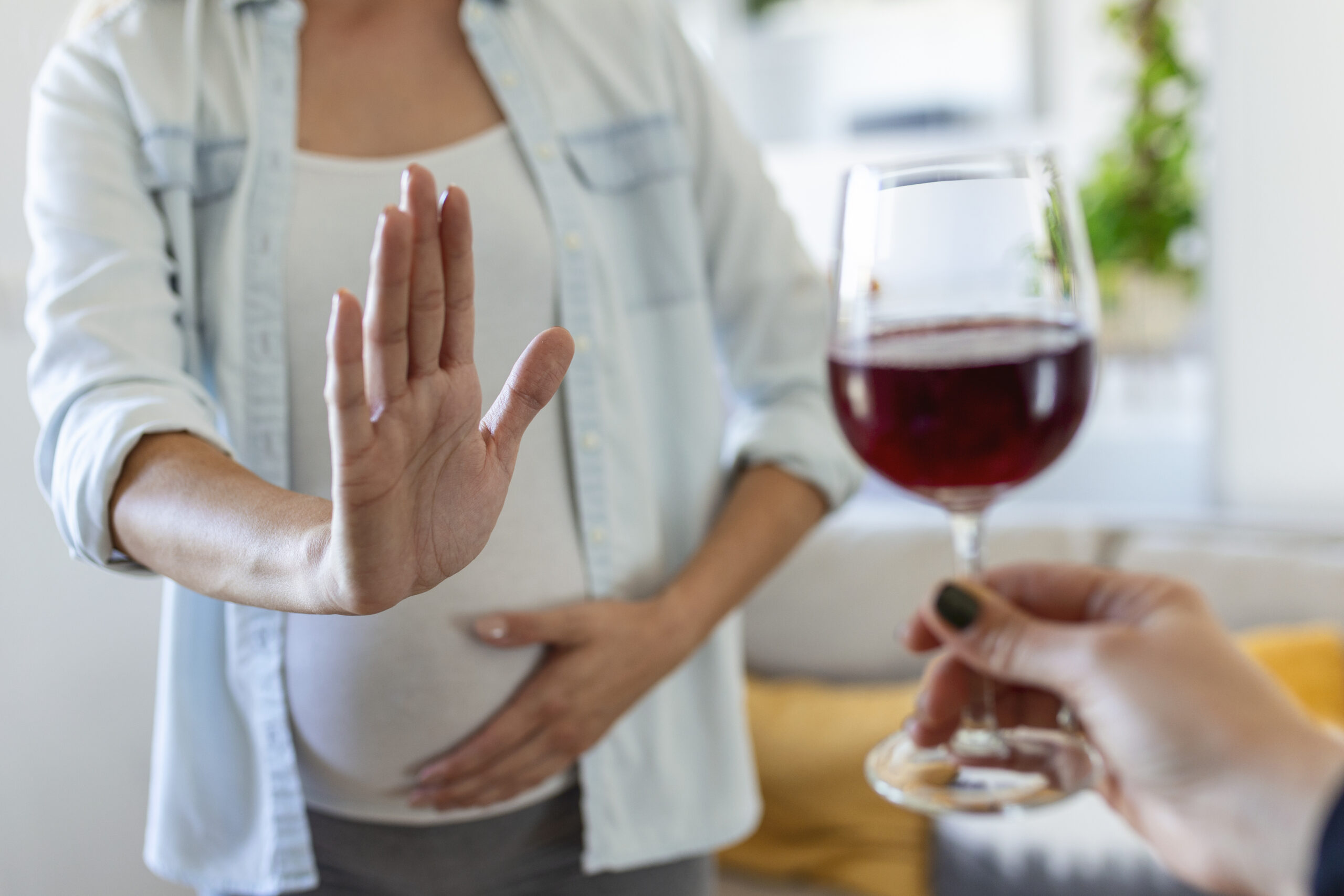 pregnant woman refusing a glass of wine. alcohol in pregnancy. unrecognizable expectant lady gestring stop to offered glass of wine