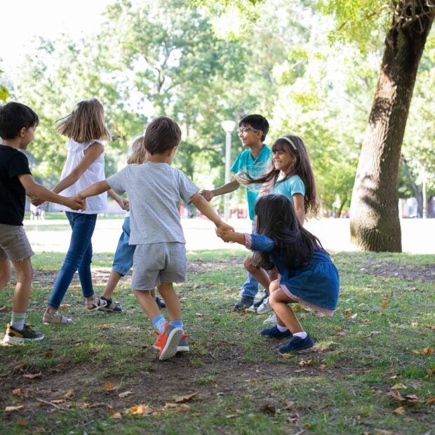 happy children playing together outdoors dancing around grass enjoying outdoor activities having fun park kids party friendship concept (1) (1)