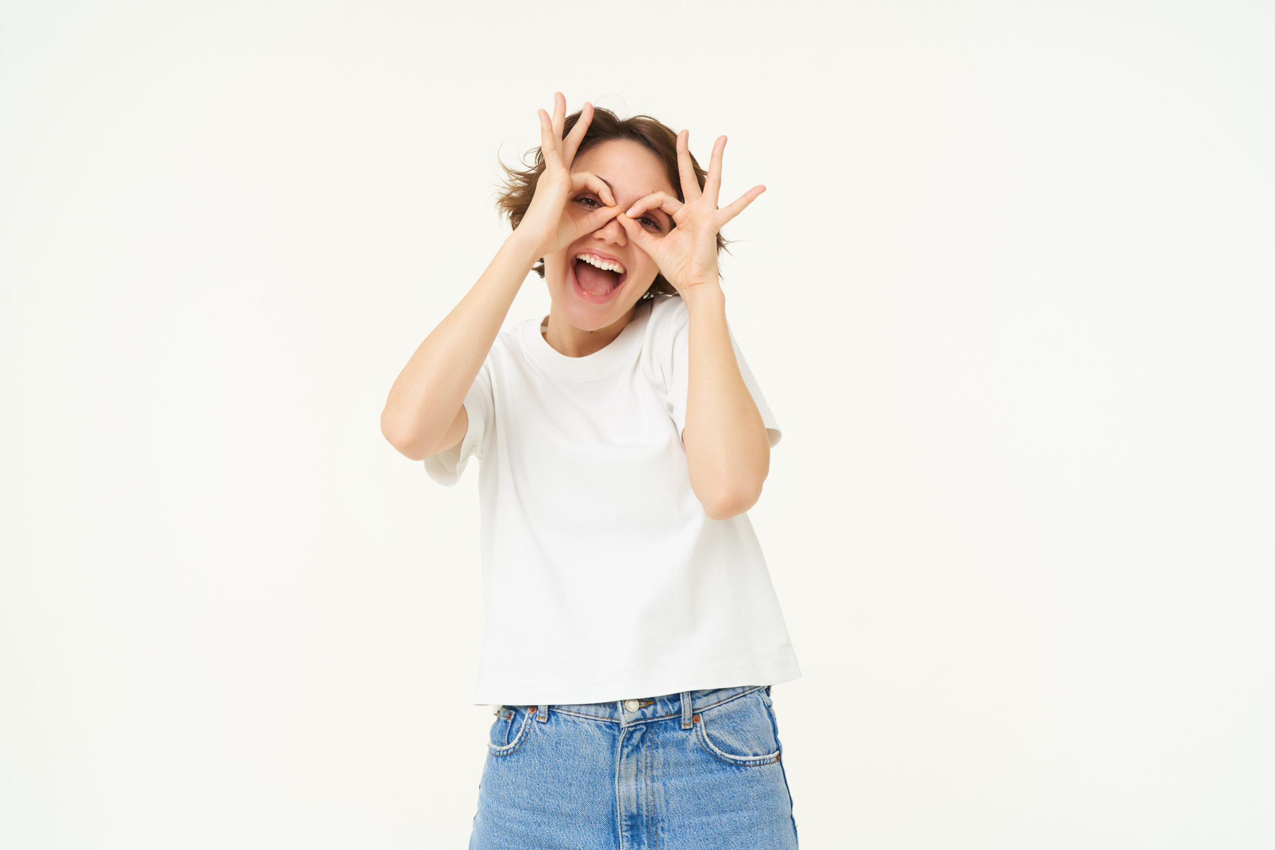 portrait of carefree european woman, showing glasses with hands over eyes and smiling, posing over white background