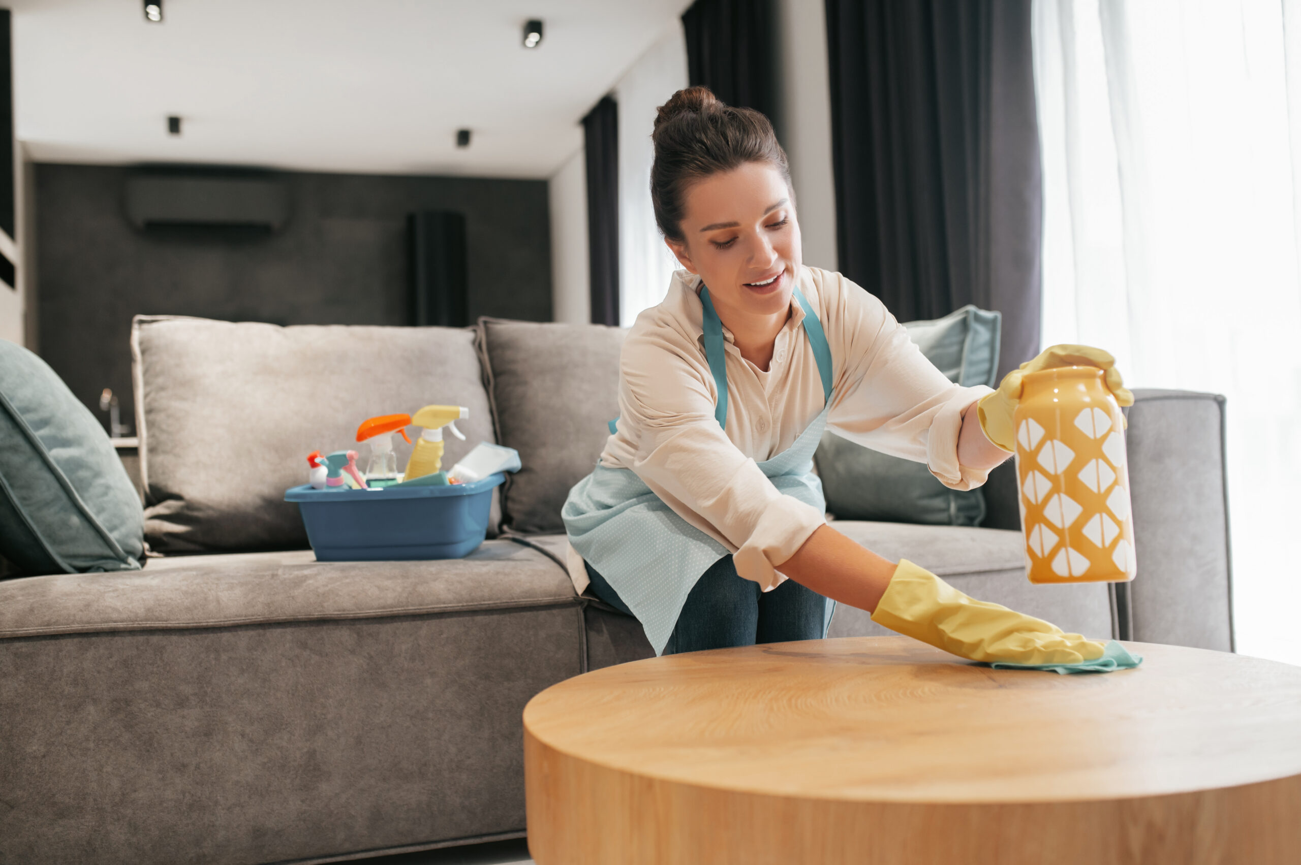 a woman cleaning a table surfcase with disinfector