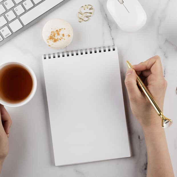 feche mao segurando uma caneta dourada e um copo