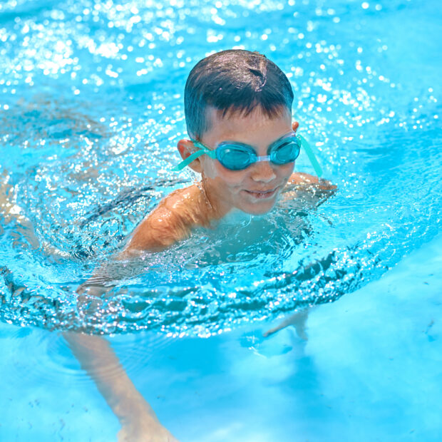 boy in goggles swimming in pool