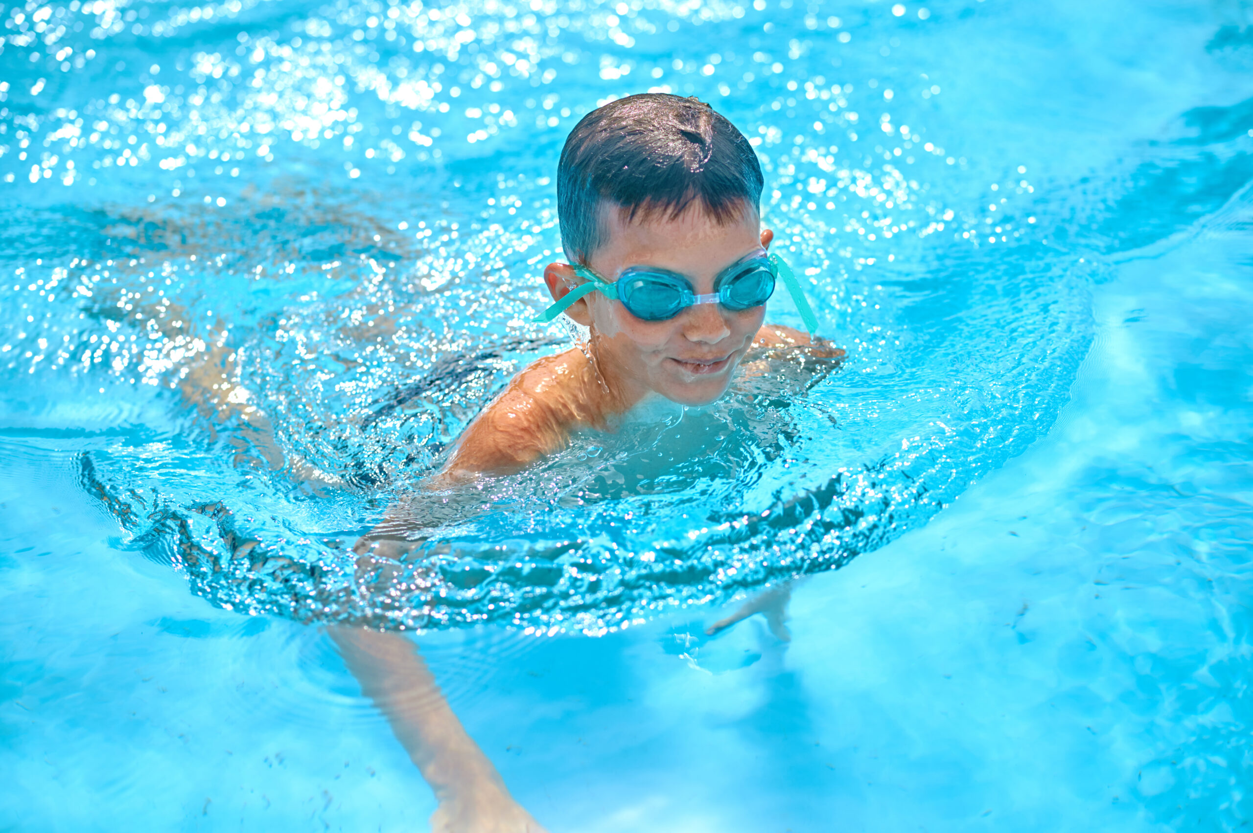 boy in goggles swimming in pool