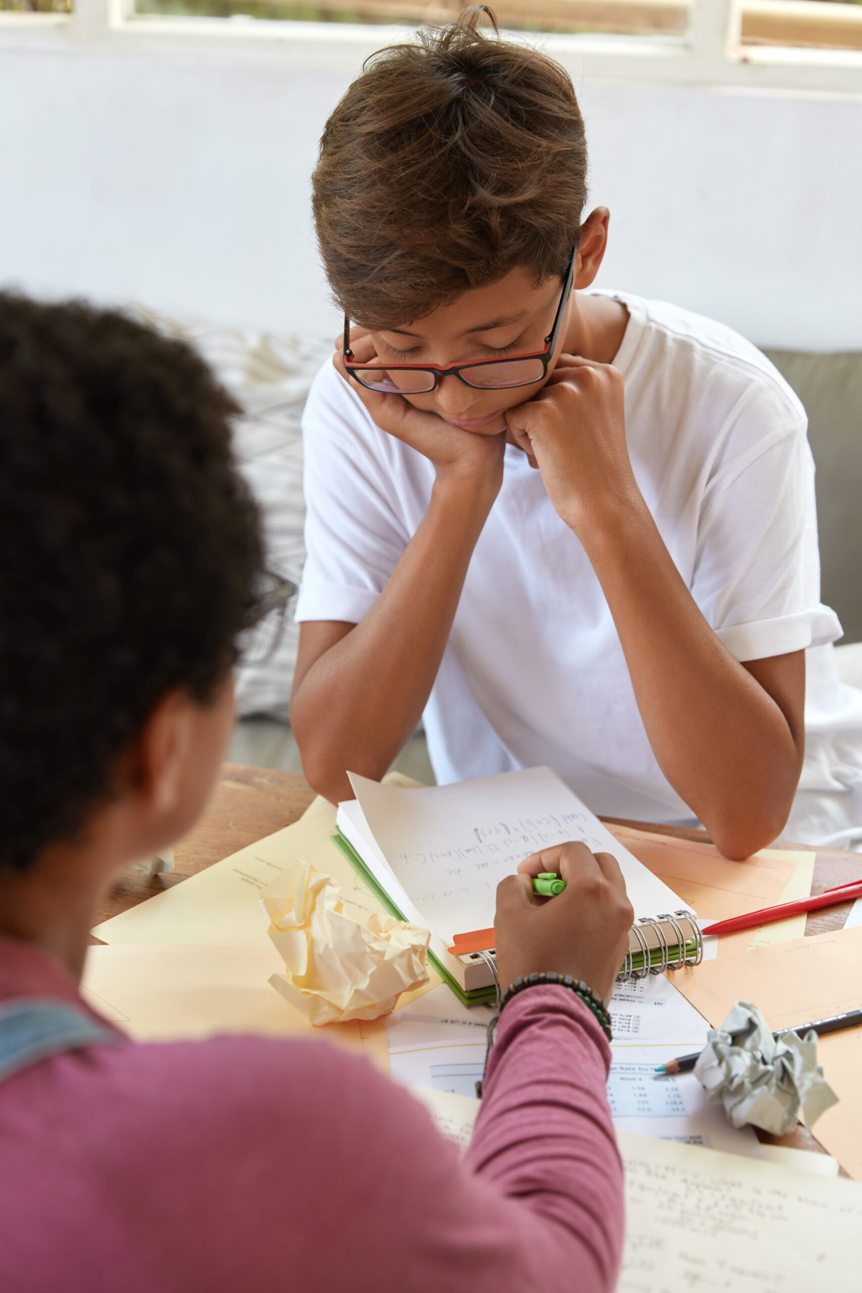 education, teaching and learning concept. older sister explains how make task to brother who studies at school, points at notes in spiral diary, sit in coworking space. training teacher and student