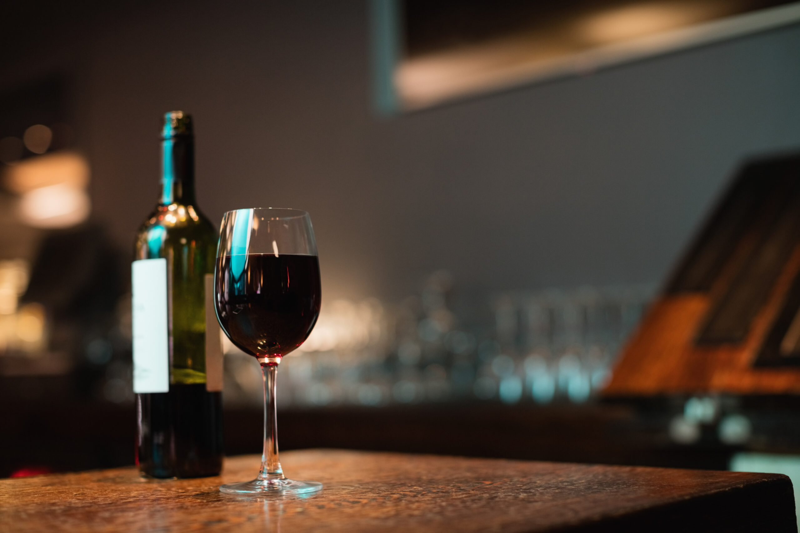 glass of red wine and bottle on bar counter at bar
