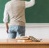 math teacher writing chalkboard near table with books