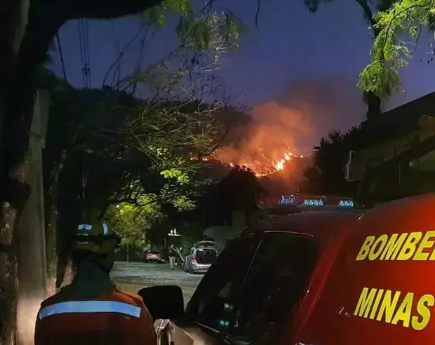 imagem mostra parta da lateral do carro do corpo de bombeiros militar da corporacao aparece de costas ao lado do carro ao fundo e possivel ver o fogo na serra 2 52361