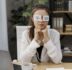young businesswoman covering her eyes with drawn eyes paper