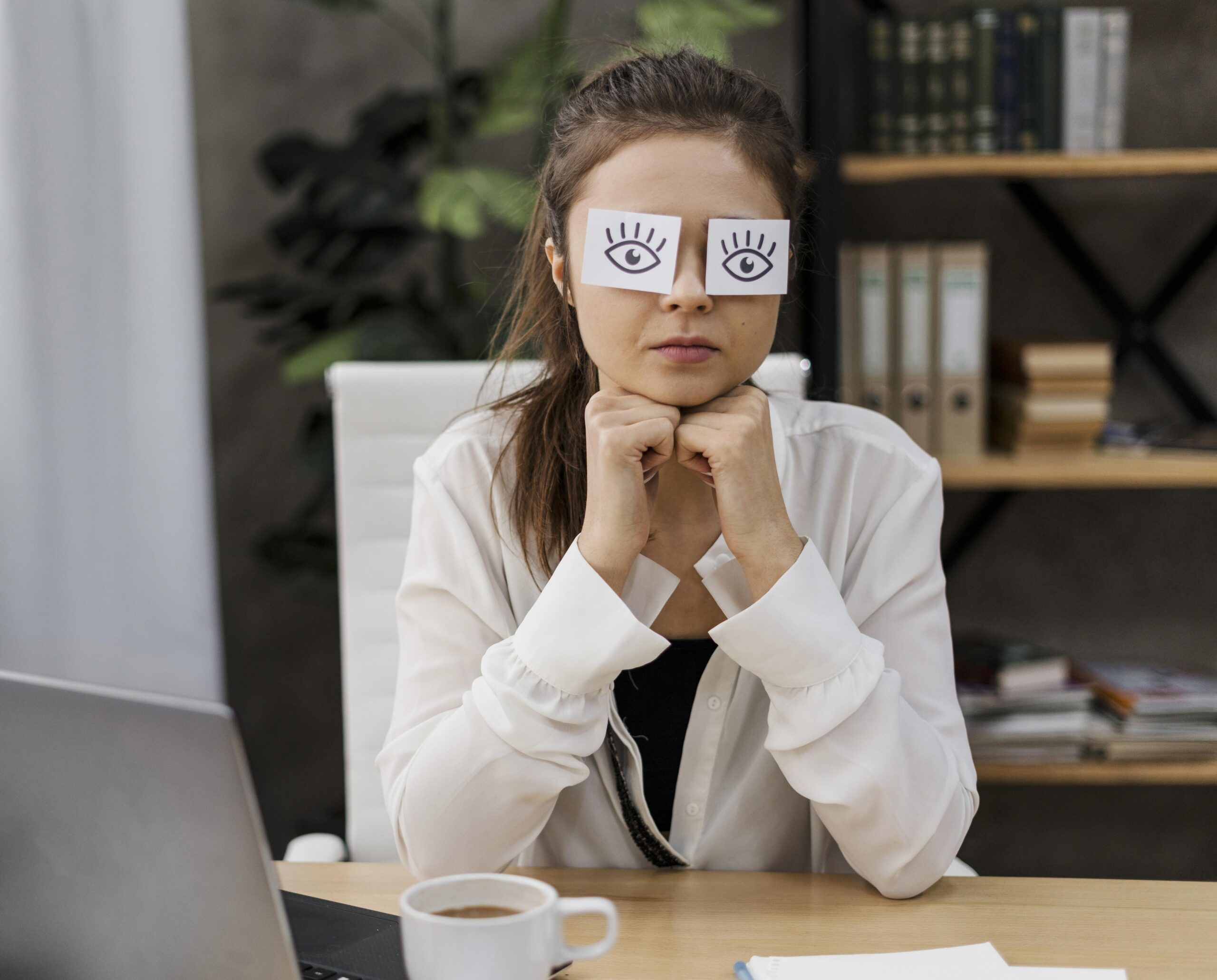 young businesswoman covering her eyes with drawn eyes paper