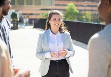 smiling caucasian woman talking to friends on street