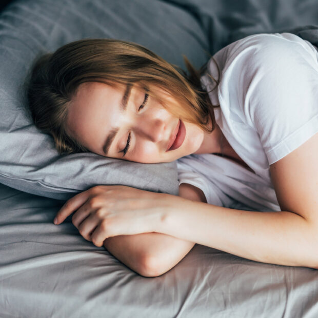 beautiful young smiling woman sleeping in bed