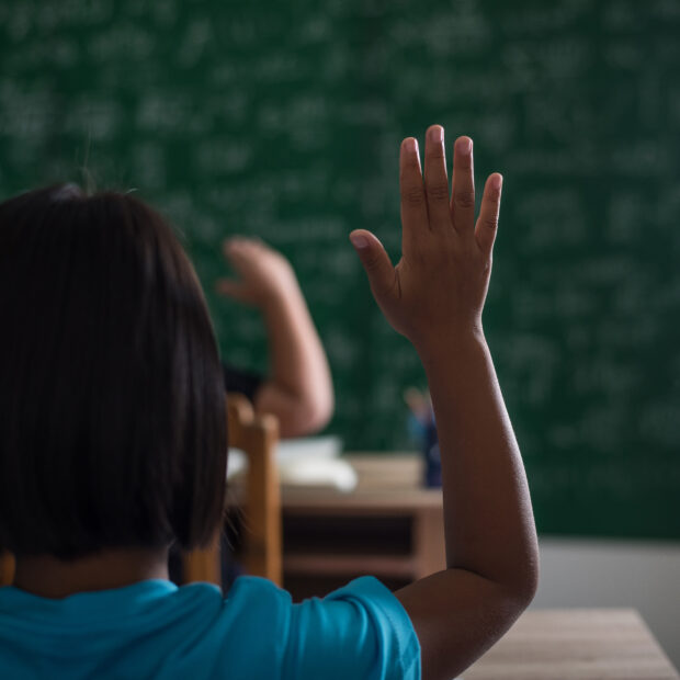kid raising his hand in classroom