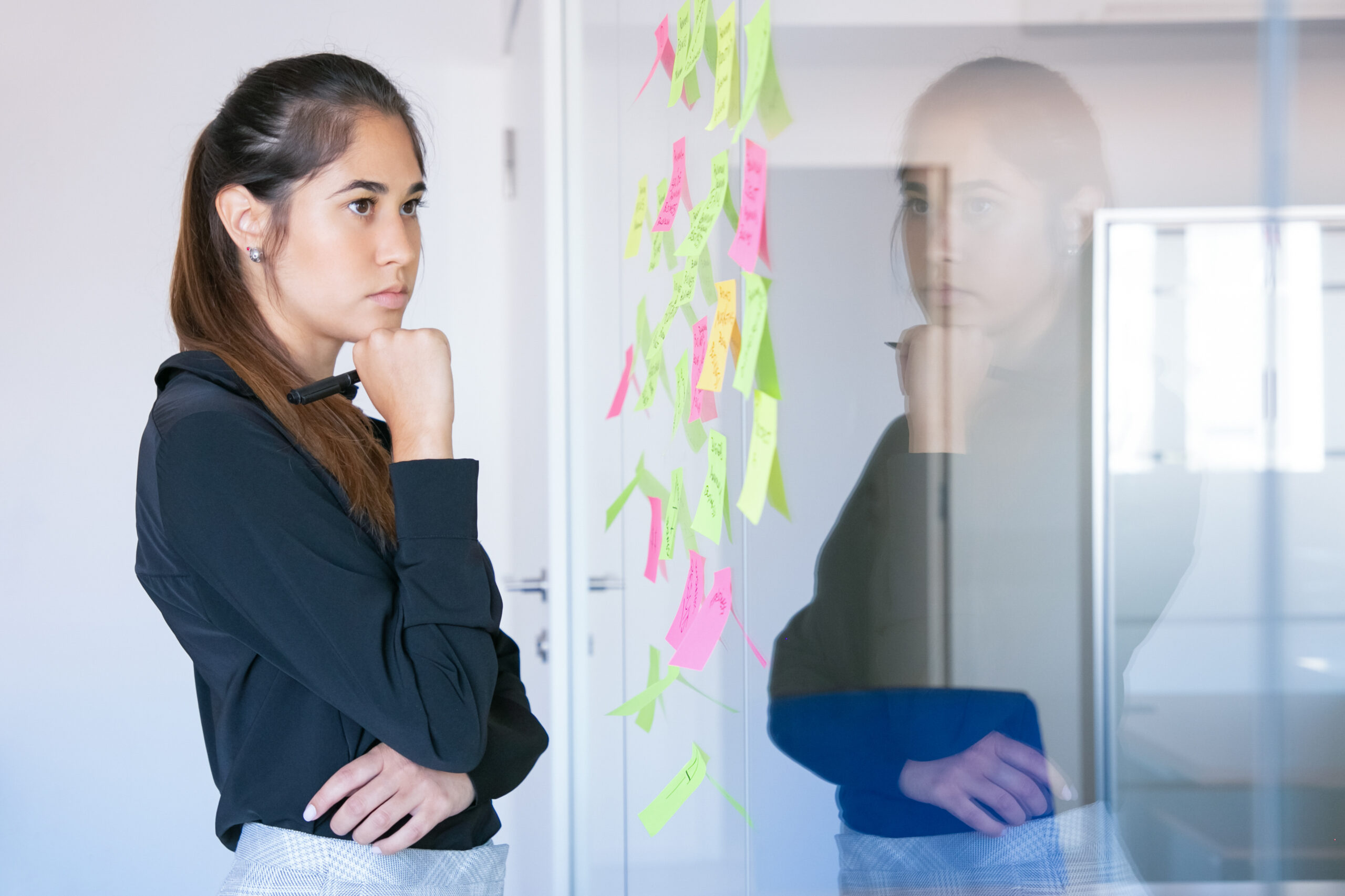 thoughtful latin businesswoman holding marker and reading notes