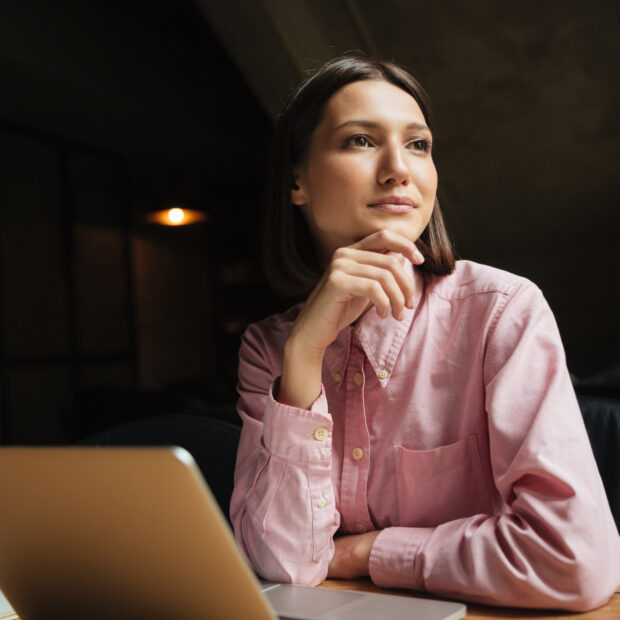 smiling pensive woman sitting by the table in cafe