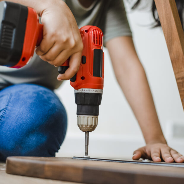 woman using hand drill to assemble a wooden table