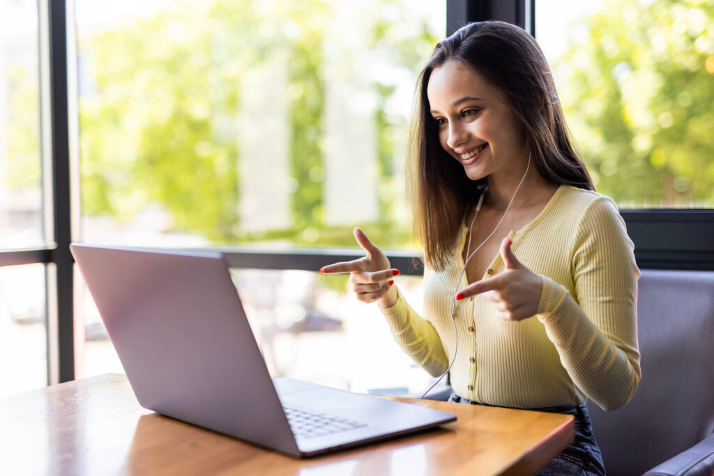 beautiful freelancer female talking in a video conference on line and laptop in an office desktop or home desk