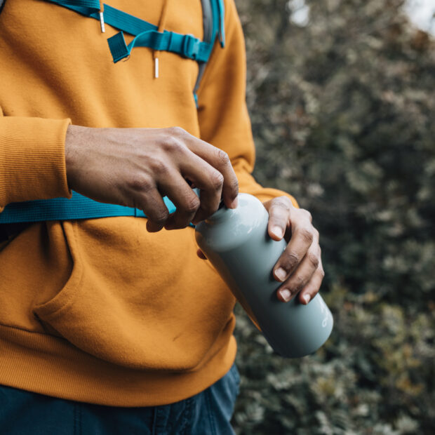 mid section man opening lid water bottle
