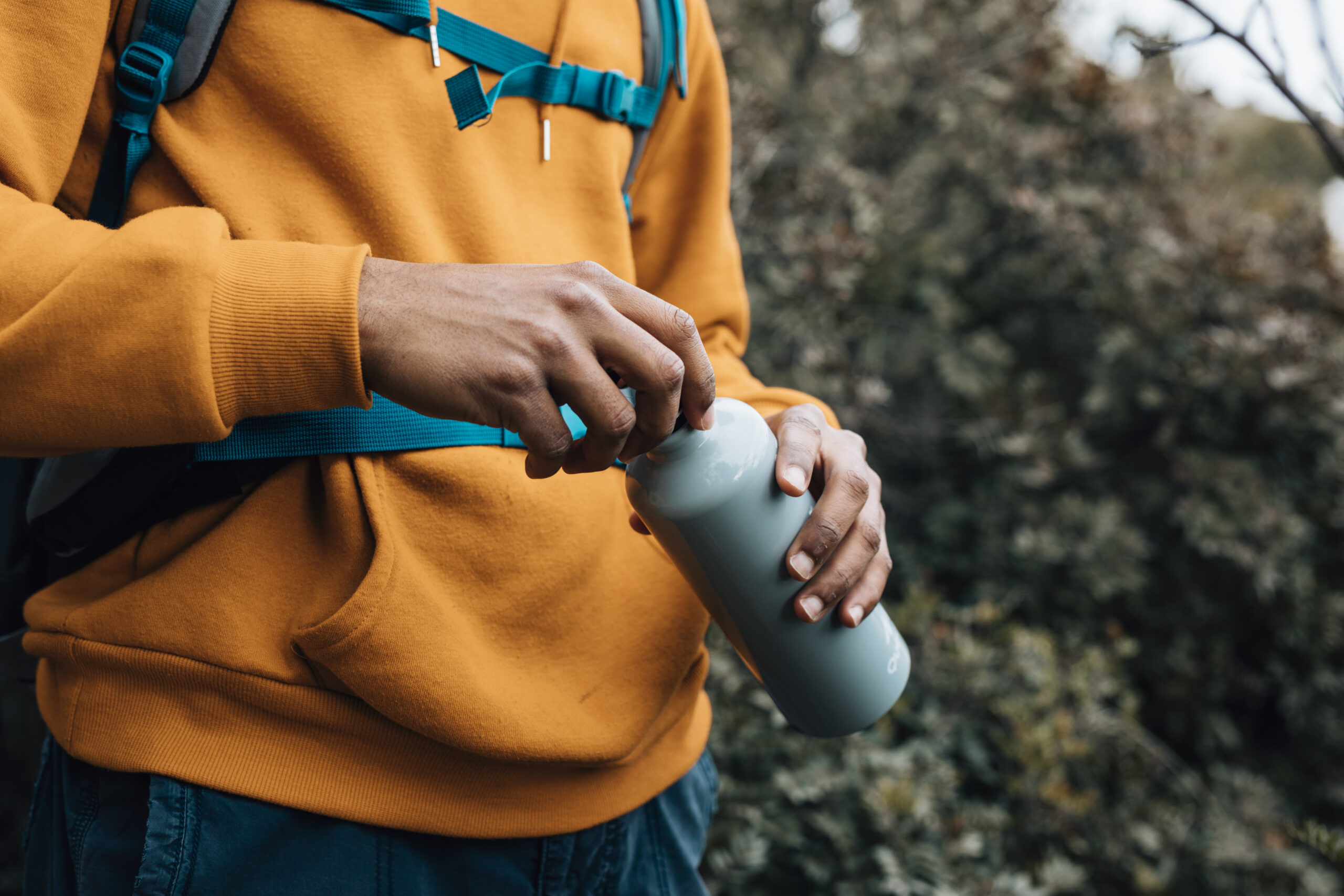 mid section man opening lid water bottle