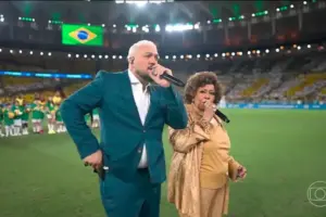 O que era para ser um dos momentos mais emocionantes da noite acabou virando assunto nas redes após Belo e Alcione se desencontrarem durante a execução do Hino Nacional. - Reprodução TV Globo