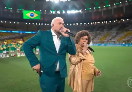 O que era para ser um dos momentos mais emocionantes da noite acabou virando assunto nas redes após Belo e Alcione se desencontrarem durante a execução do Hino Nacional. - Reprodução TV Globo