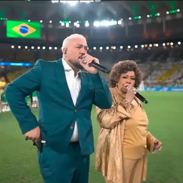 O que era para ser um dos momentos mais emocionantes da noite acabou virando assunto nas redes após Belo e Alcione se desencontrarem durante a execução do Hino Nacional. - Reprodução TV Globo