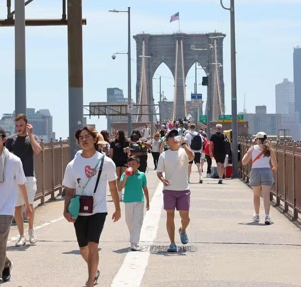 107384789 new york new york june 20 people walk along the brooklyn bridge amid a heat wave on june
