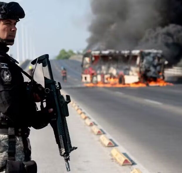 114011012 topshot a member of the prosecutors office stands guard near a burning bus at one of th