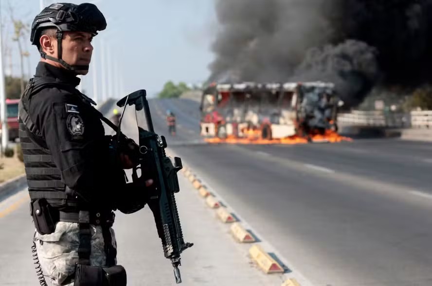 114011012 topshot a member of the prosecutors office stands guard near a burning bus at one of th
