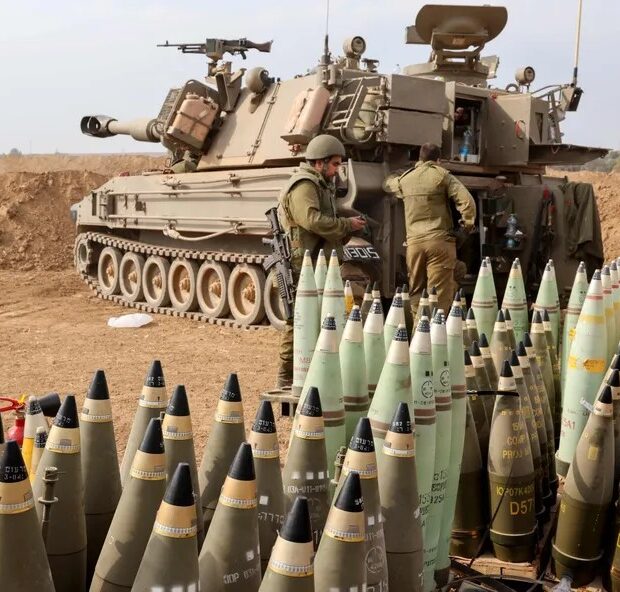 104621428 artillery shells are lined up next to an armoured vehicle as israeli soldiers take pos