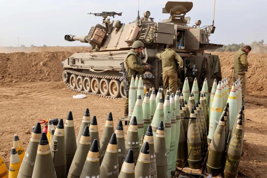 104621428 artillery shells are lined up next to an armoured vehicle as israeli soldiers take pos