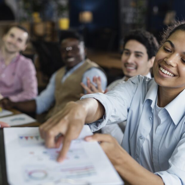 smiley woman showing graph office with coworkers