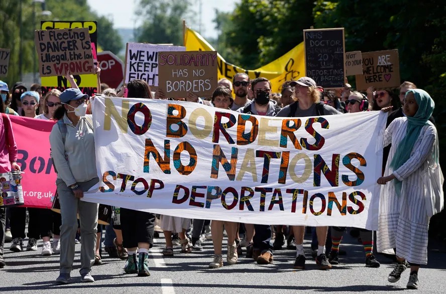 99534132 protesters hold up placards as they march towards the brook house immigration removal c