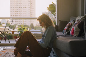 side view young woman sitting carpet using laptop home