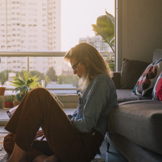 side view young woman sitting carpet using laptop home