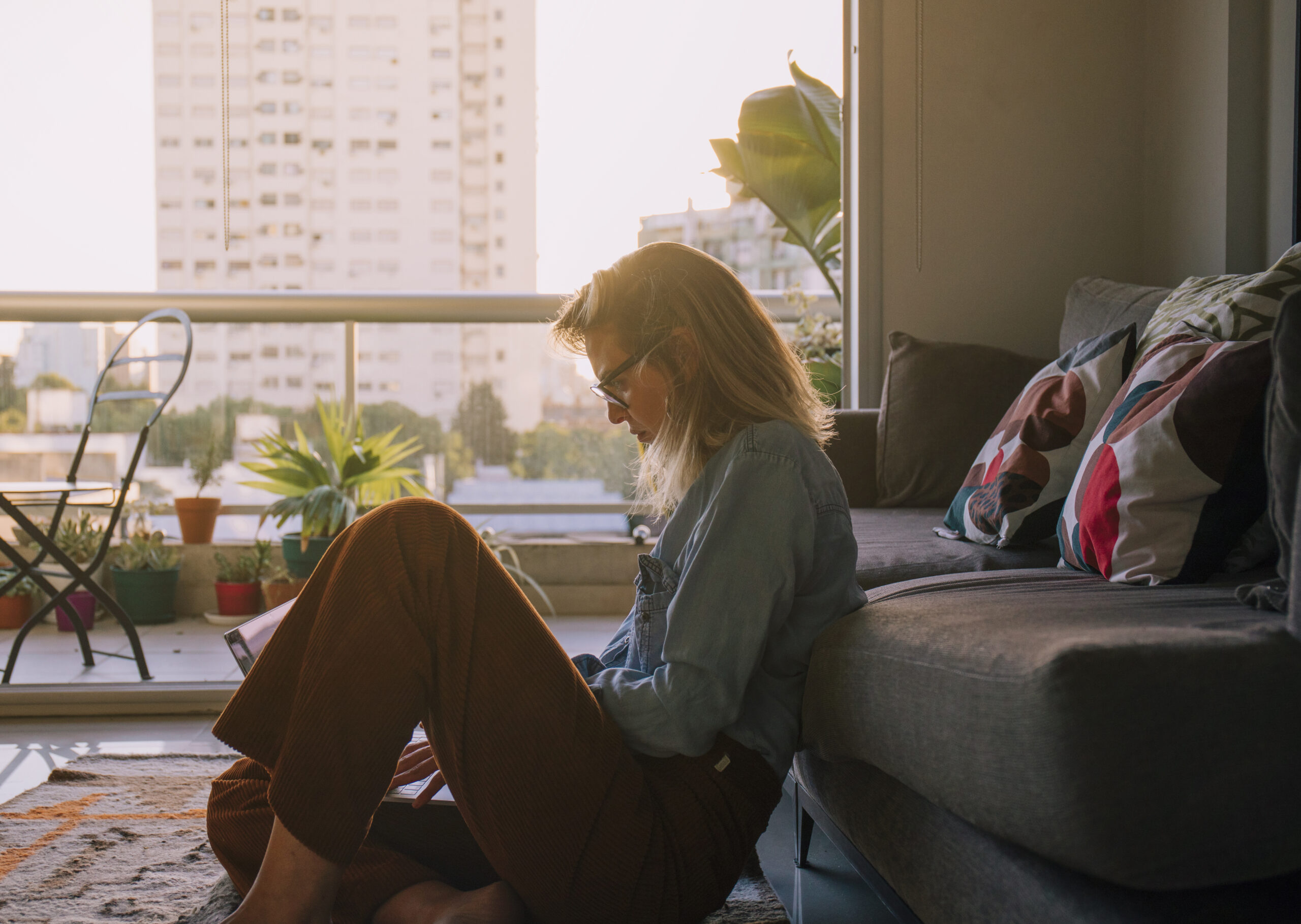 side view young woman sitting carpet using laptop home