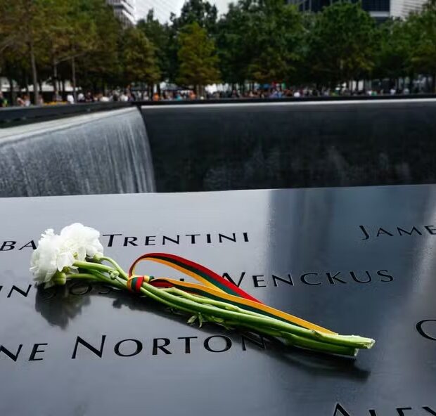116174948 flowers are left on the side of the reflecting pool as visitors gather around the 9 11 mem