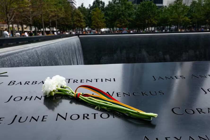 116174948 flowers are left on the side of the reflecting pool as visitors gather around the 9 11 mem
