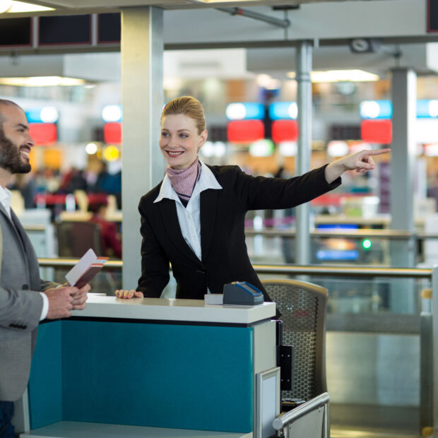 airline check in attendant showing direction to commuter at check in counter in airport terminal