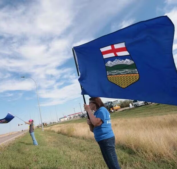 116438238 separatists waves the alberta flag by the roadside during an event advocating for alberta