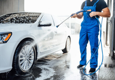 professional washer blue uniform washing luxury car with water gun open air car wash